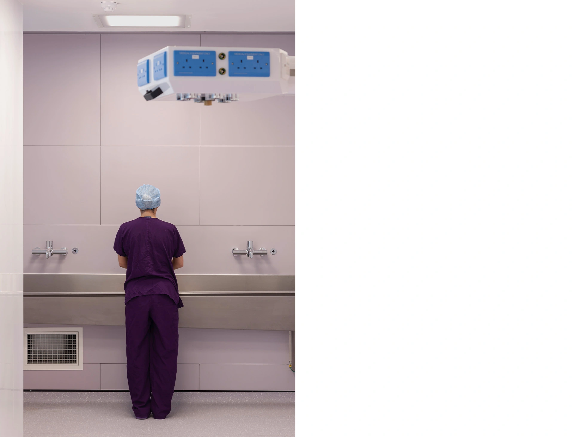Modern minimalist double-height operating theatre with large metal sinks and state-of-the art equipment.