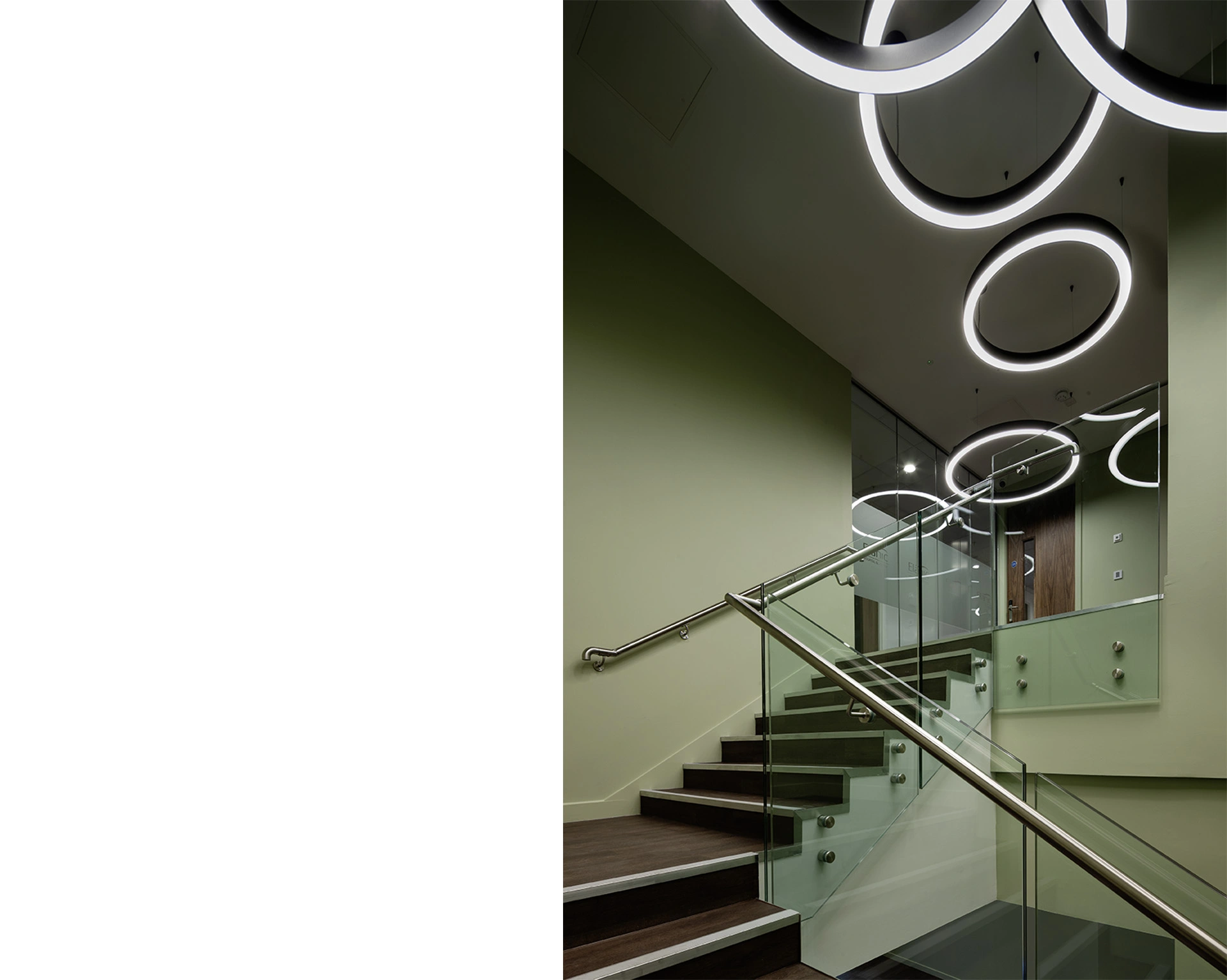 Award-winning healthcare architecture in Glasgow's Elanic Hospital glass handrail staircase with modern circle lights creating a beautiful floating effect for patient comfort.