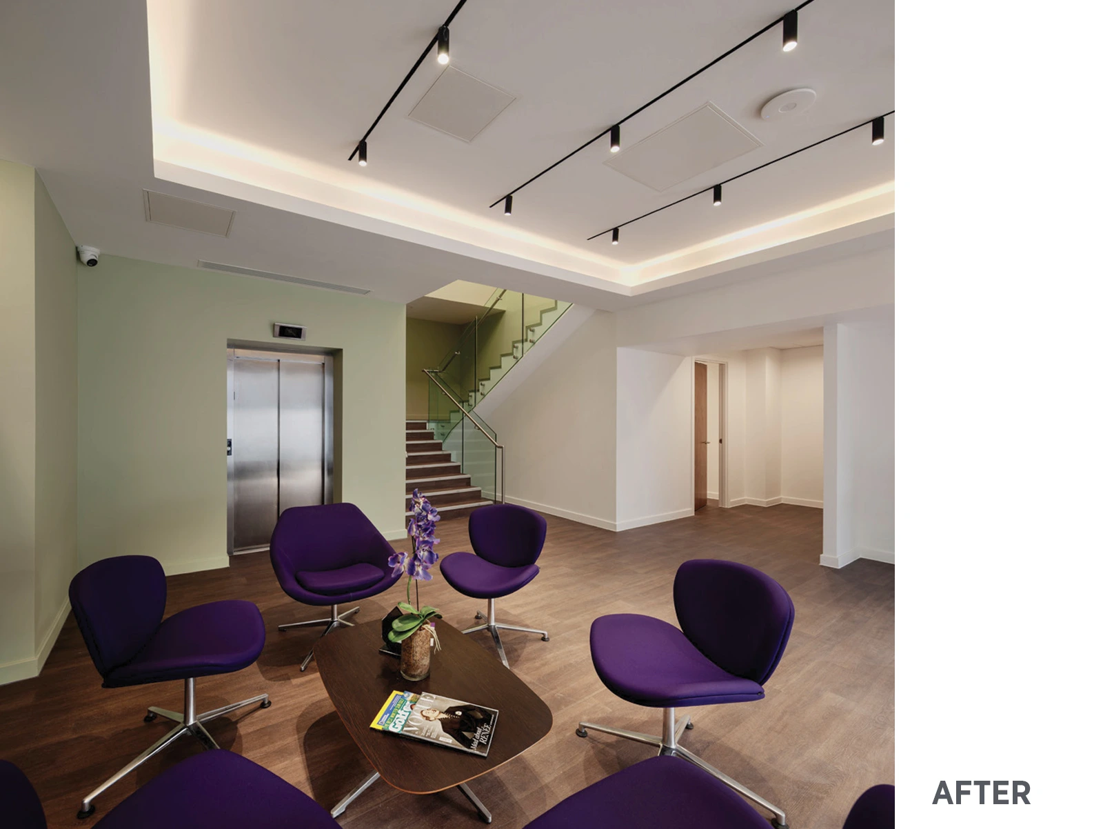Interior of hospital reception with white ceiling with LED lights, dark purple seating and stairs with glass railing and timber floor.