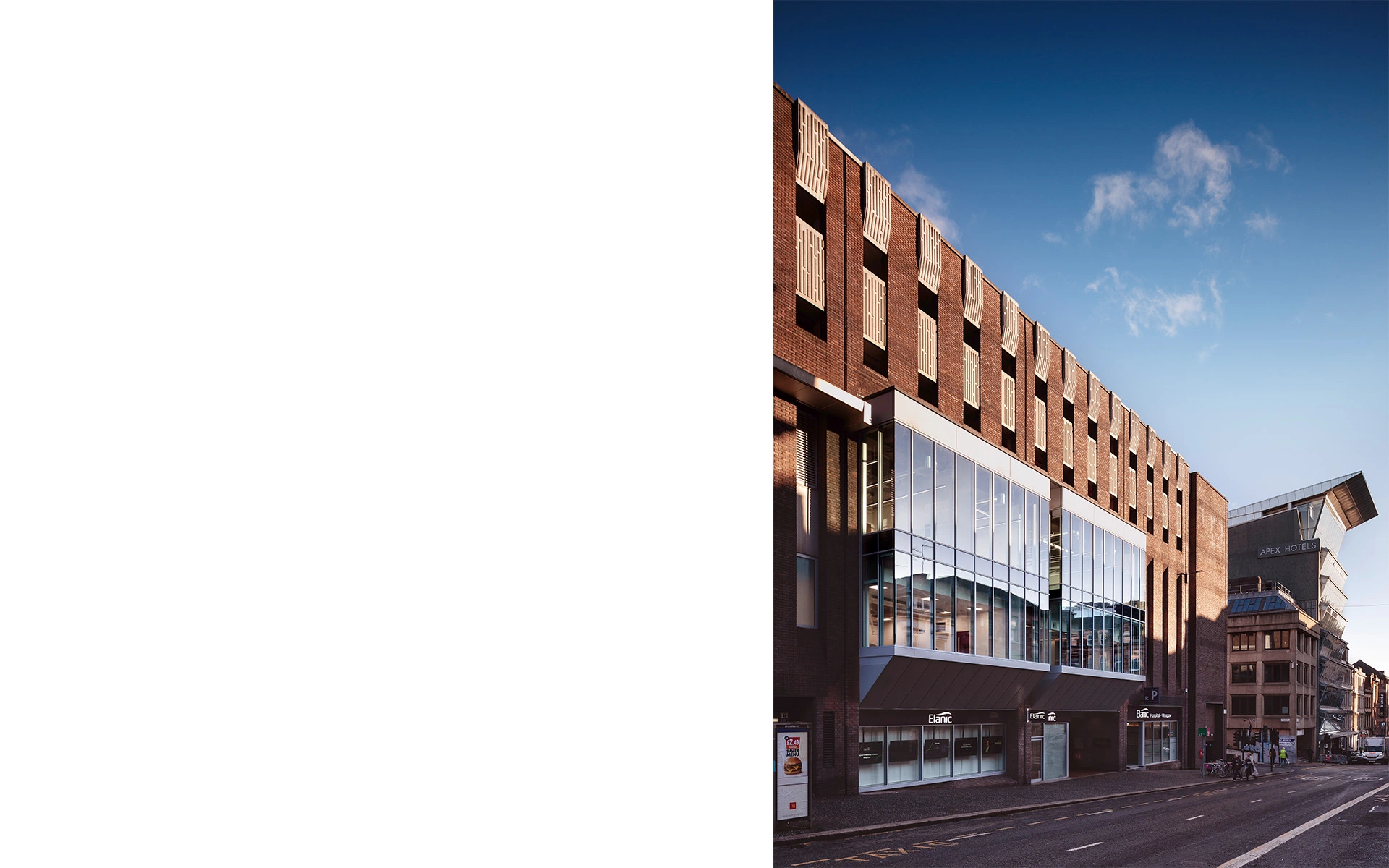 Sustainable repurposed brick brutalist hospital with large glass façade behind which operating theatres are visible on Glasgow Bath street City Centre, side angle with the sun set lighting the brown brick façade and illuminating in the large curtain wall windows.