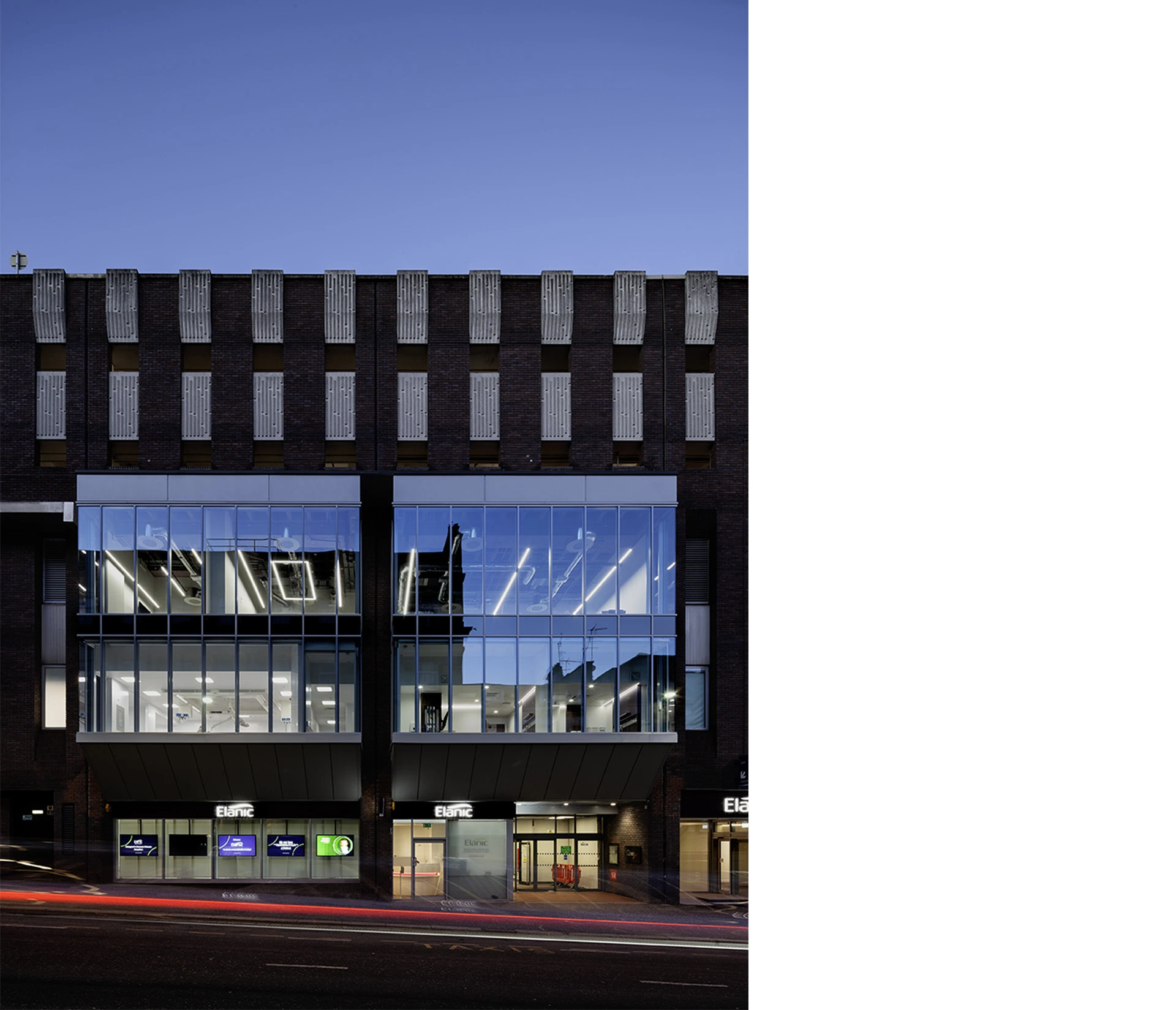 Sustainable repurposed brick brutalist hospital with large glass façade behind which operating theatres are visible on Glasgow Bath street City Centre, at night with bright lights illuminating the indoor spaces and surgery theatres.