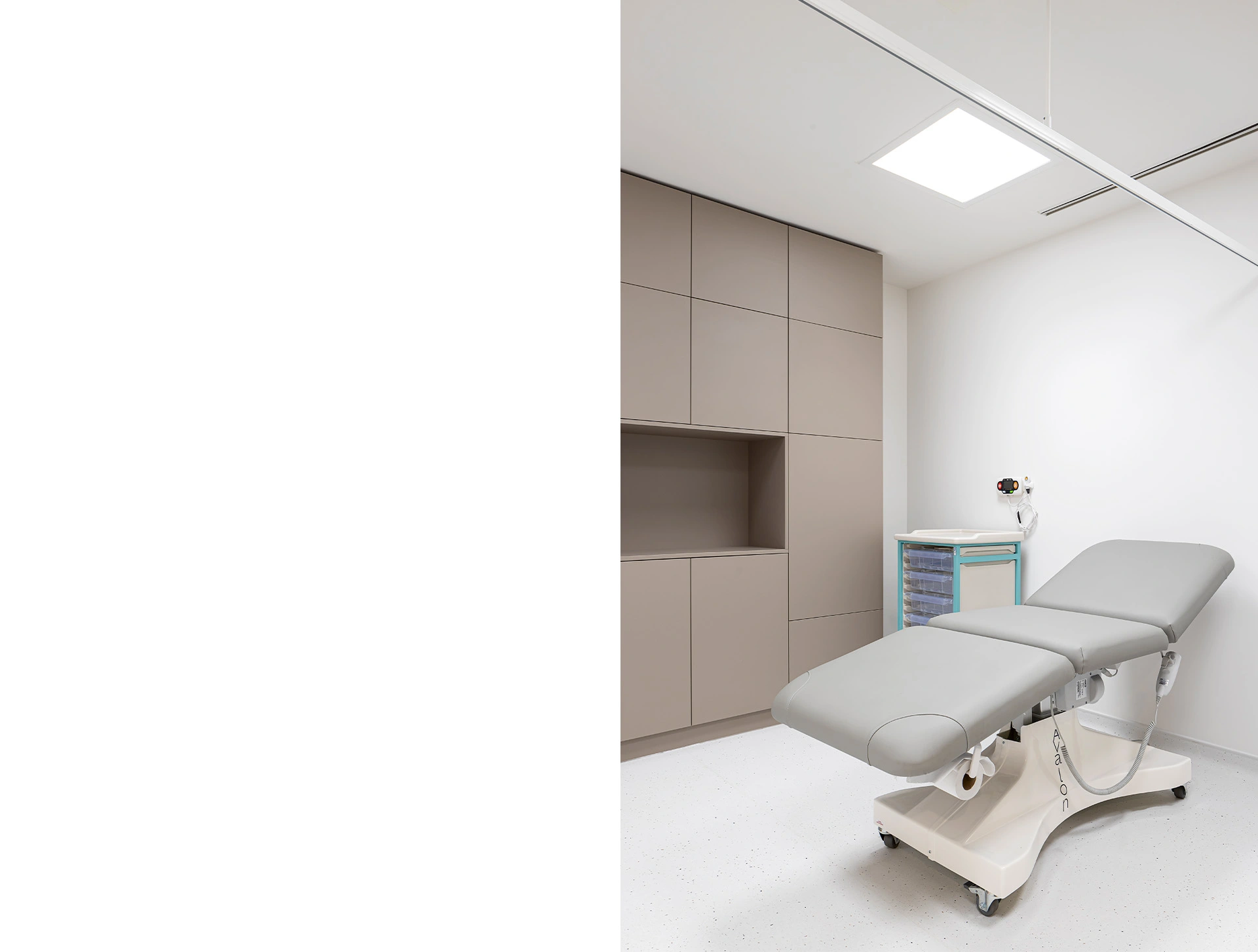 A photo of a bespoke recovery clinic hospital room with grey wall cupboards and a light grey recovery bed. Medical equipment is visible in the background and specialised lighting is used throughout. This private hospital room was designed by NVDC bespoke healthcare architects.