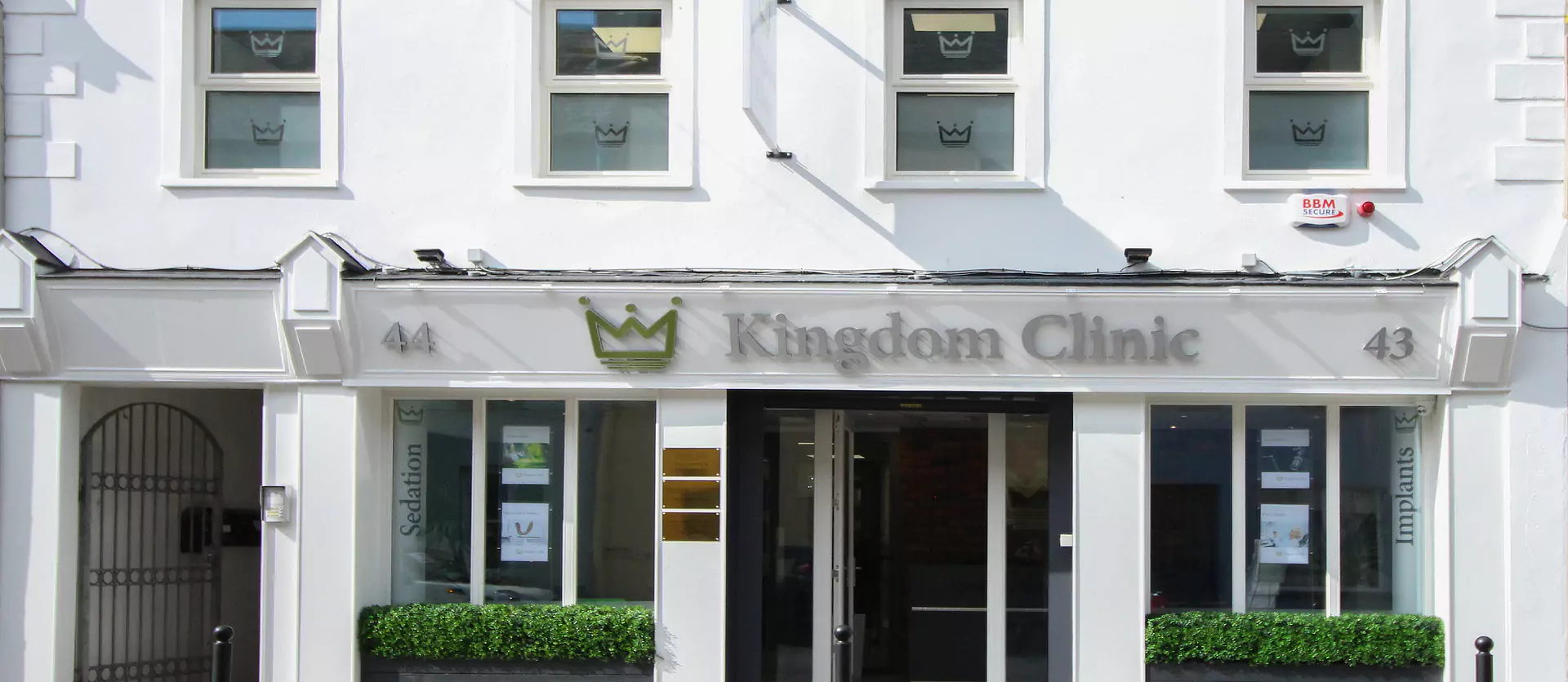 A white two-storey front building of a modern dental medical healthcare clinic with a calm small-town atmosphere.