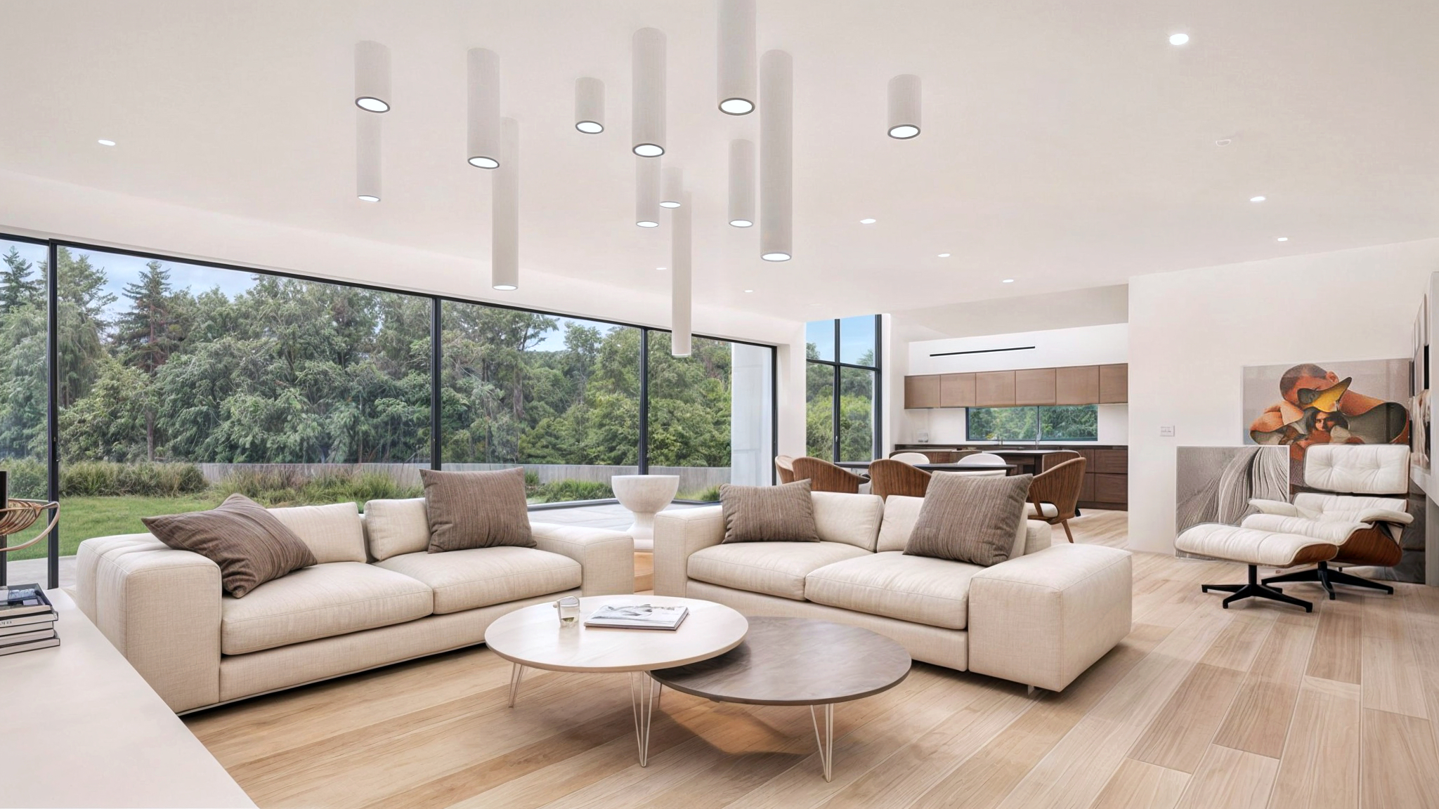 3D of an open-plan-living interior of a living room with a large white sofa, and round wooden tables in front of it, blond hardwood floors and a white comfortable sofa chair next to it. The soft white furniture complements the white walls and ceiling, with creative tubular lights and floor-to-ceiling glazed window wall showcasing views towards the spacious garden in the back and letting in lots of natural light and making the home cosy and comfortable. This substantial home remodelling and renovation project is executed by NVDC Architects Glasgow Scotland UK. The bright open space is modern and luxurious.