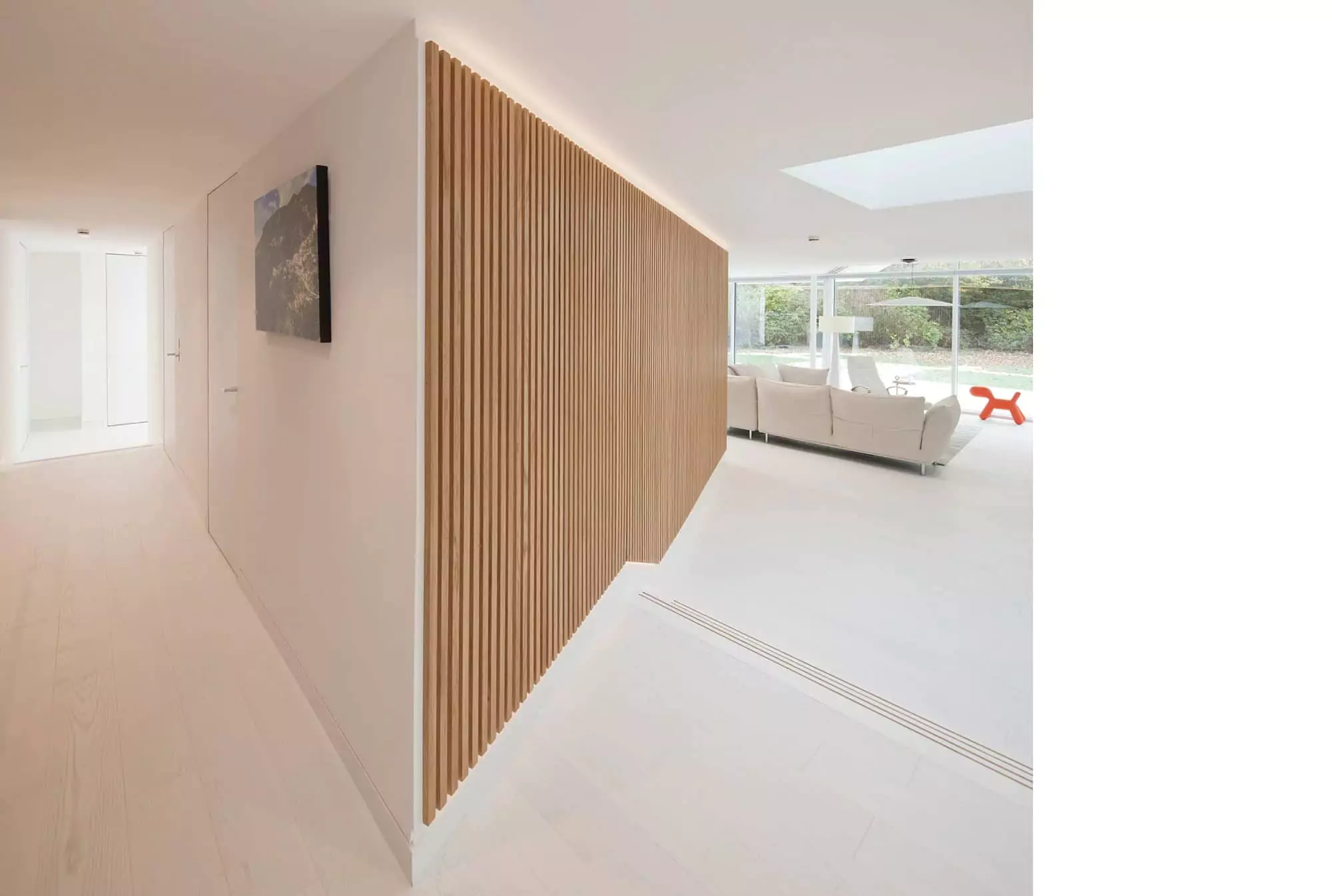 Sleek and modern interior design of a Glasgow home extension, featuring a white colour palette, slatted wood accent walls, and expansive floor-to-ceiling windows. The open-plan living area is flooded with natural light, enhanced by strategically placed rooflights and LED lighting, showcasing the expertise of Glasgow architects in home renovation and remodelling.